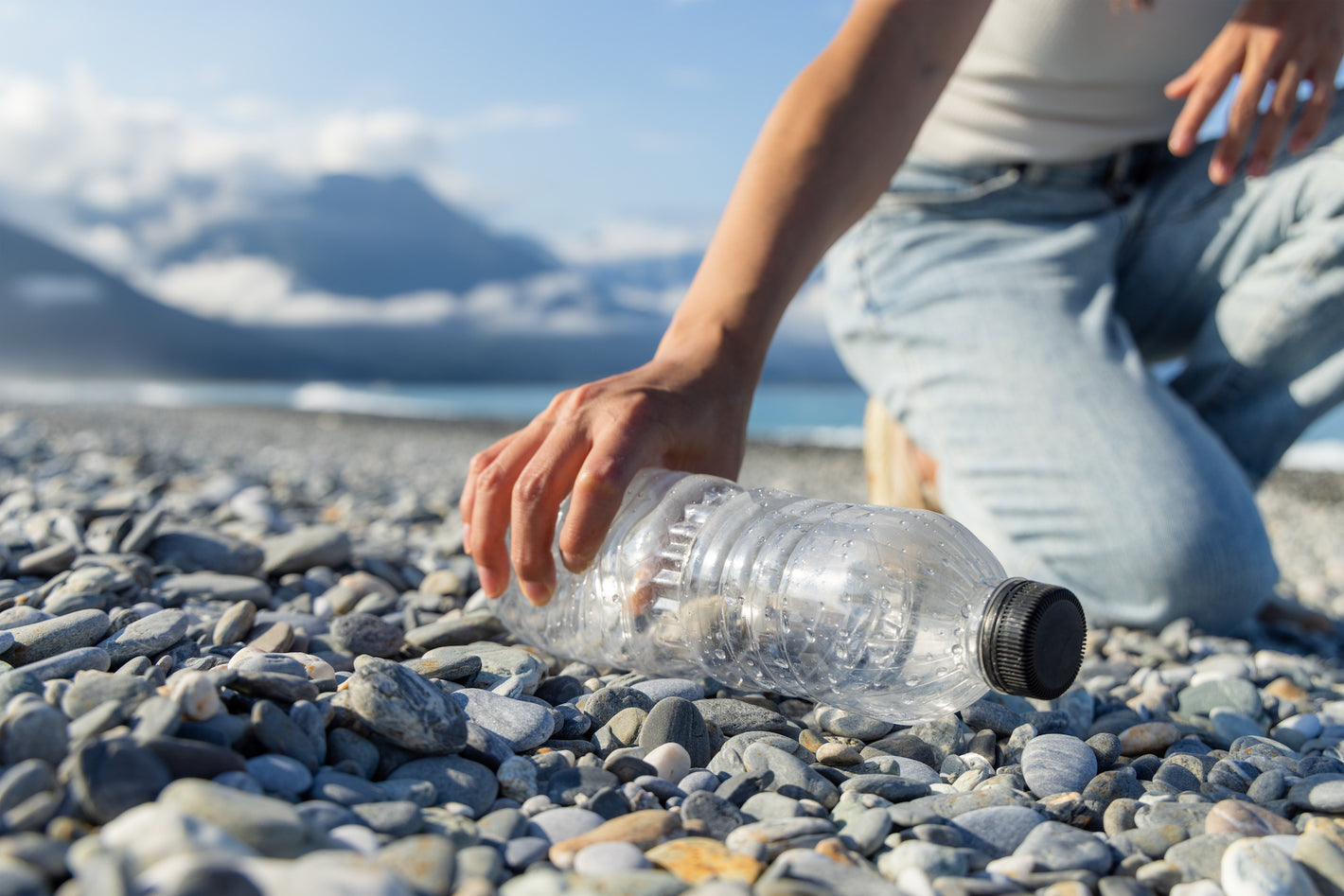 Woman hand picking up plastic bottle cleaning on the beach.